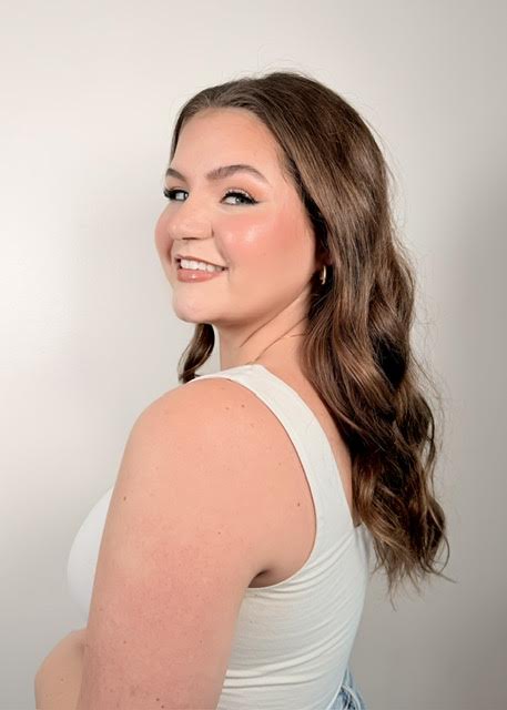 Client with soft glam makeup smiling over her shoulder.